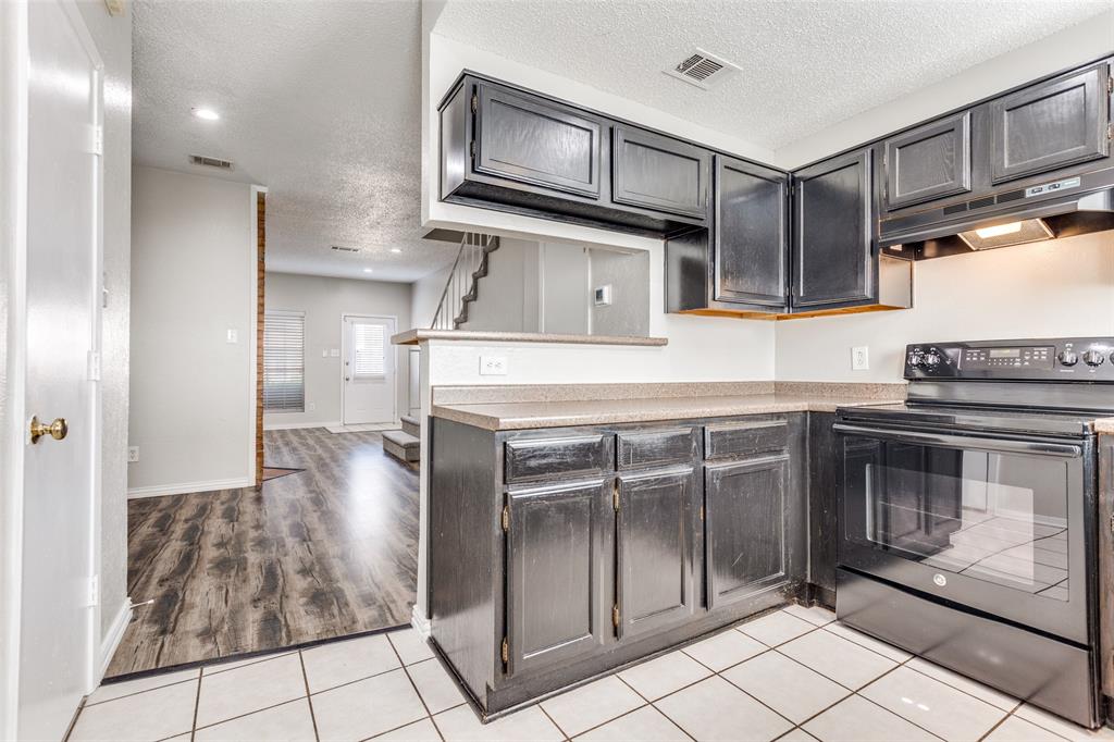 633 Carriagehouse Lane, Unit I6 Garland, TX 75040 - Photo 10 of 24 a kitchen with kitchen island granite countertop a stove a sink and a refrigerator with wooden cabinets