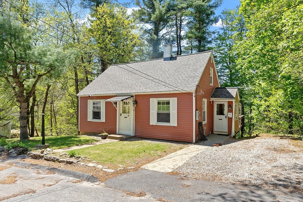 a view of a house with a yard plants and large tree