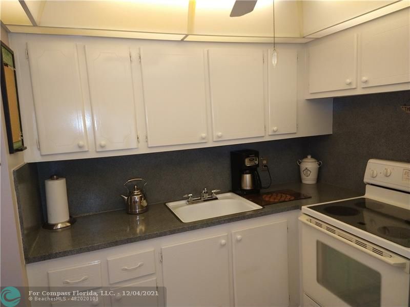 287 Markham M, Unit 287 Deerfield Beach, FL 33442 - Photo 26 of 64 a kitchen with granite countertop a sink a stove and cabinets
