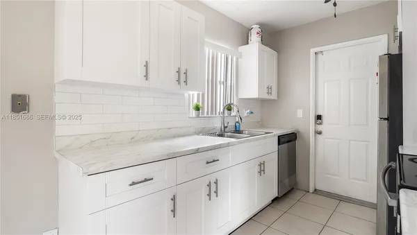 a kitchen with white cabinets and sink