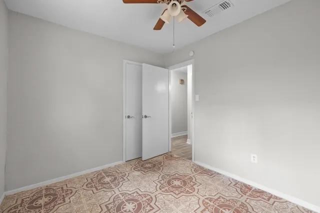 an empty room with a window and a ceiling fan