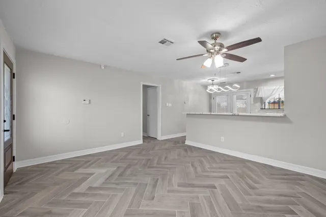 a view of an empty room with a chandelier fan and a window