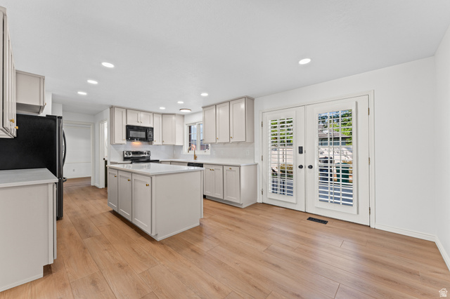 8441 Rua Branco Drive Sandy, UT 84093 - Photo 8 of 47 Bright kitchen featuring light wood-finish flooring, white cabinetry with gold-tone hardware, and a center island with a white countertop