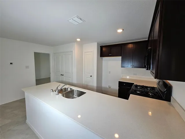a kitchen with a sink and a stove top oven with wooden floor