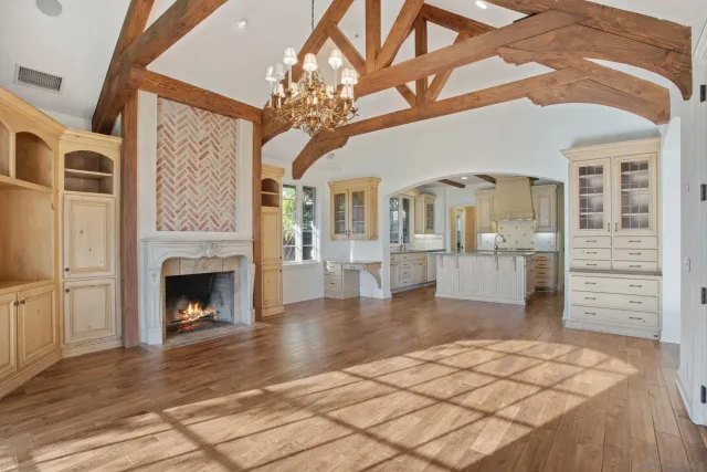 a view of a livingroom with a fireplace a chandelier and wooden floor