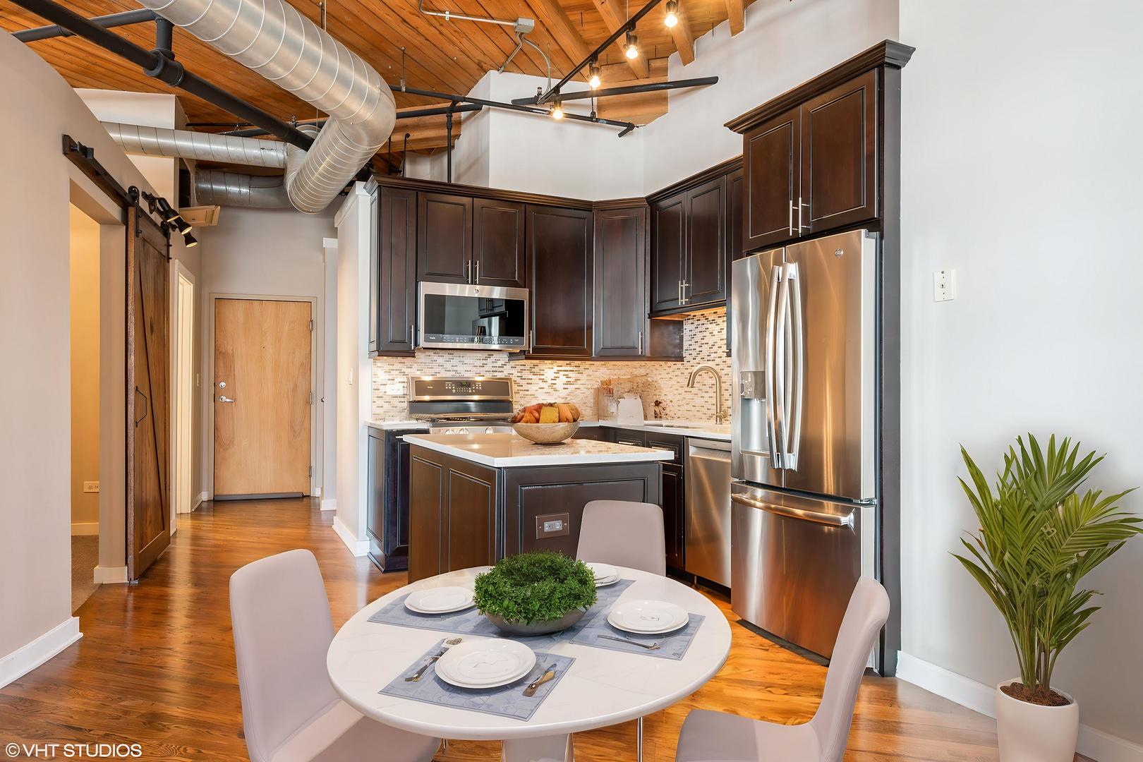 420 South Clinton Street, Unit 617A Chicago, IL 60607 - Photo 7 of 25 a kitchen with stainless steel appliances granite countertop a refrigerator a stove a sink a dining table and chairs