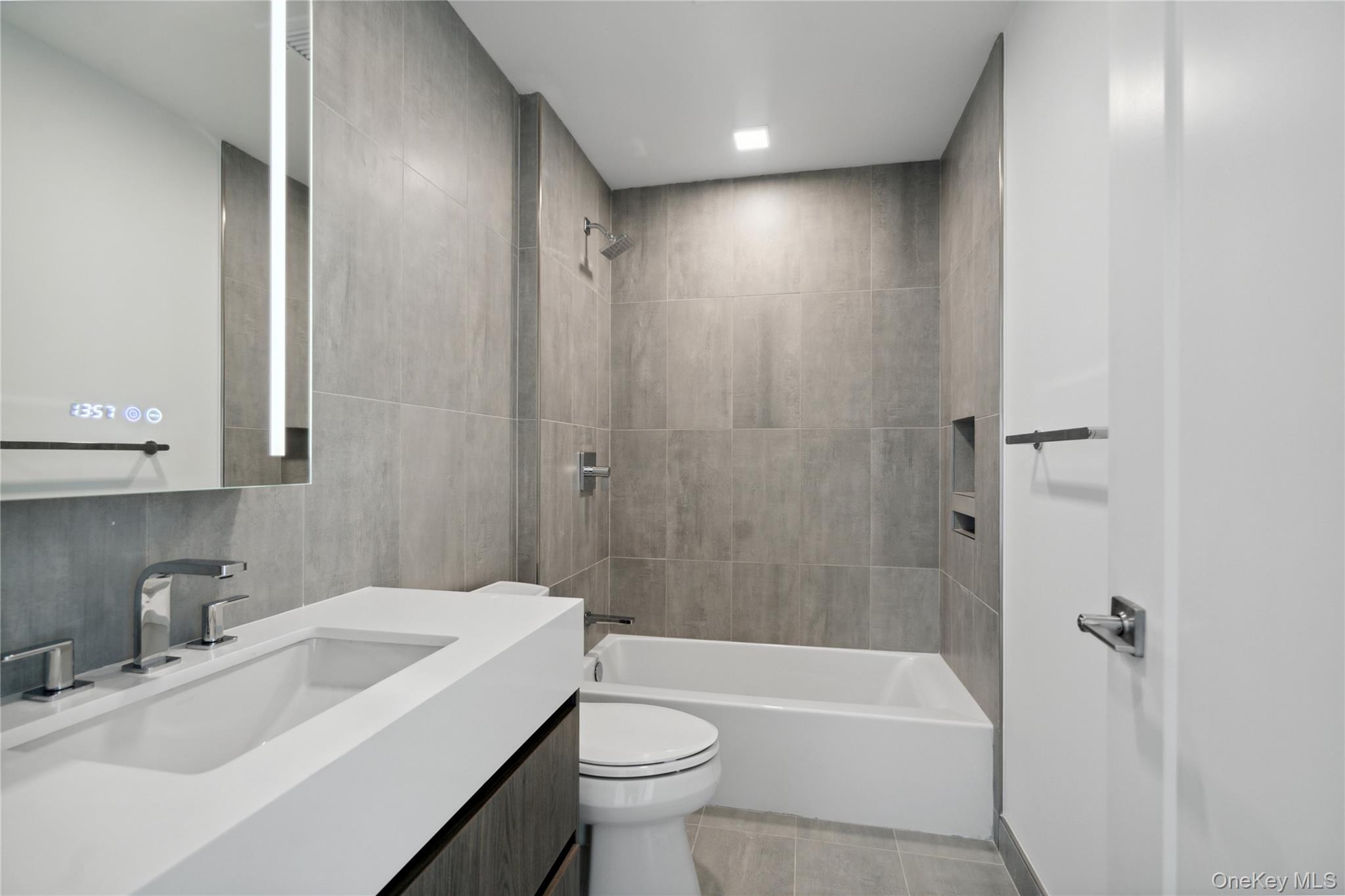 218 Middle Neck Road, Unit 101 Great Neck, NY 11021 - Photo 19 of 37 Bathroom with tile walls, toilet, vanity, and bathing tub / shower combination