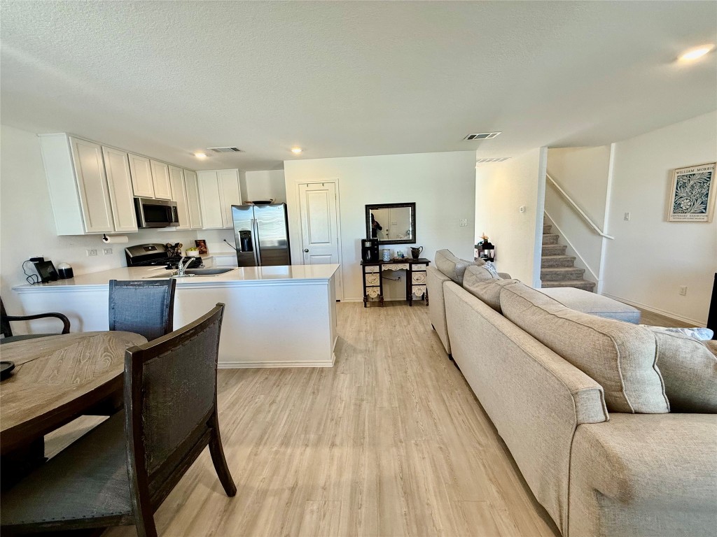 23521 Tiny Moons Way Elgin, TX 78621 - Photo 5 of 19 a living room with stainless steel appliances furniture a kitchen counter top space a sink wooden floor and view living room