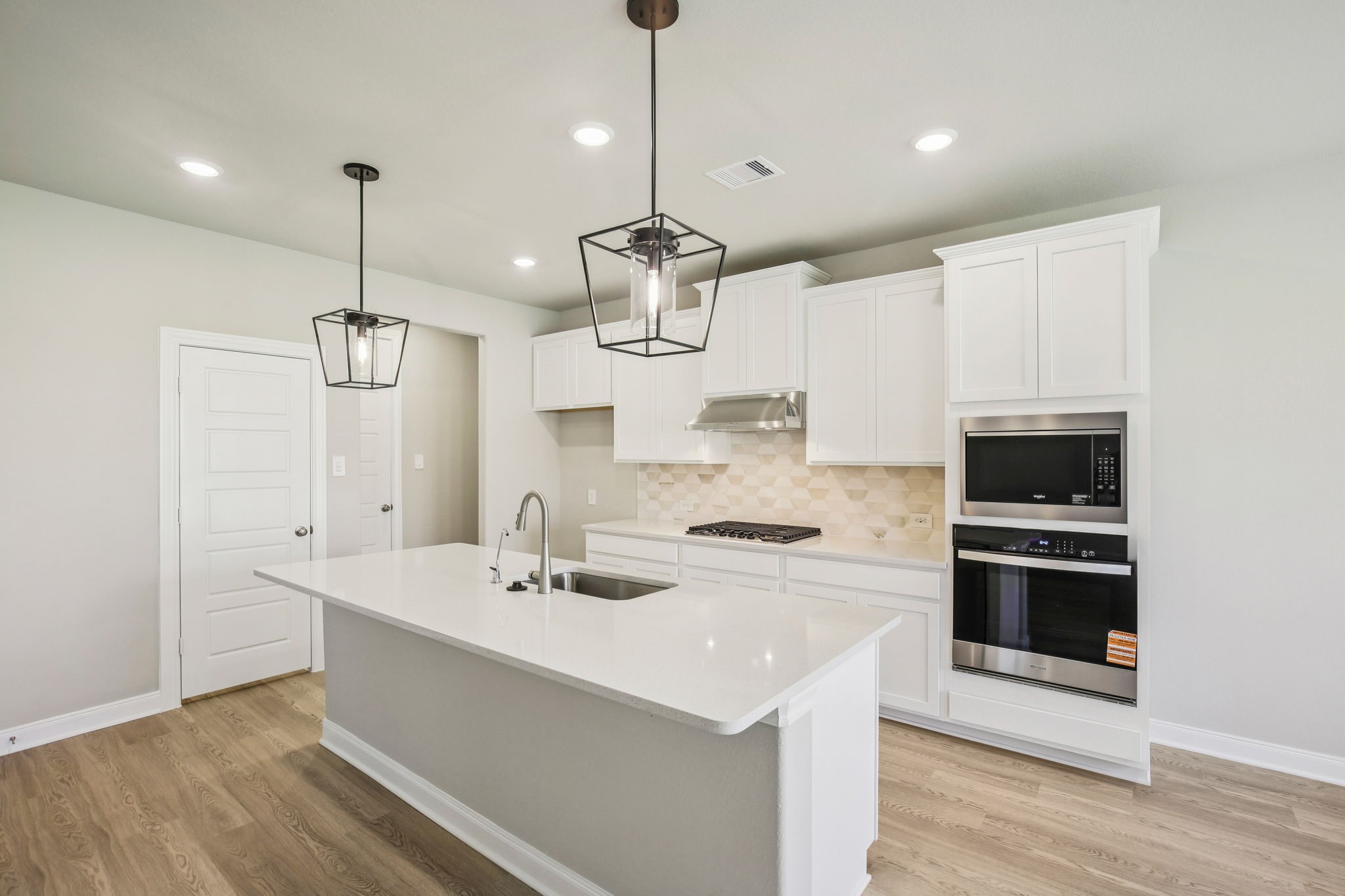 a kitchen with a sink stainless steel appliances and wooden floor