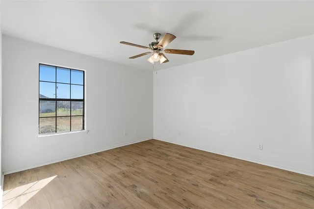 an empty room with windows and fan