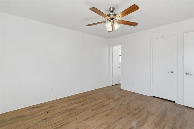 an empty room with wooden floor and a ceiling fan