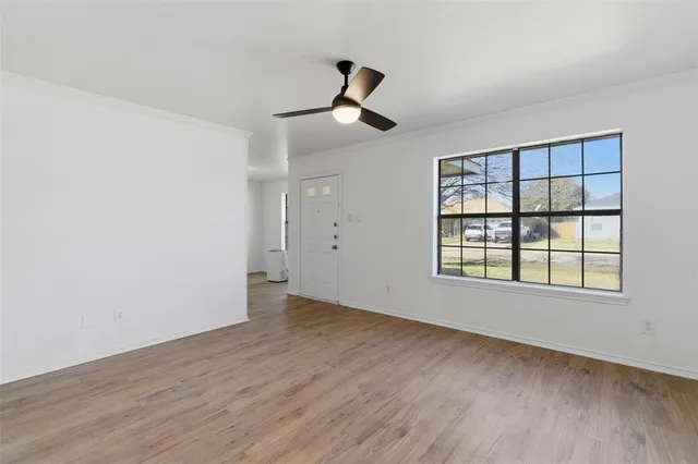 a view of an empty room with wooden floor and a window