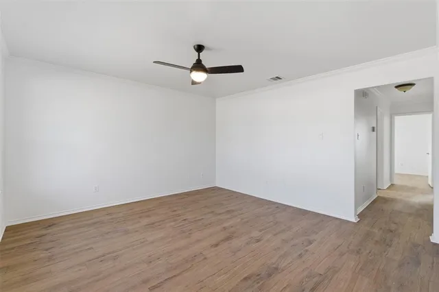 an empty room with wooden floor and ceiling fan