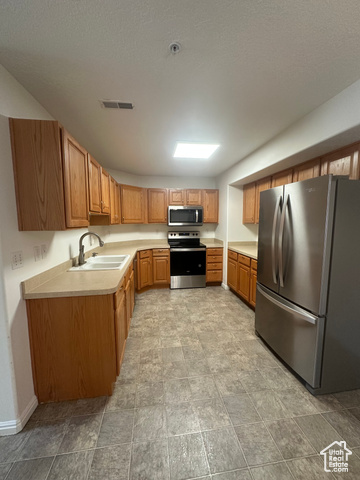 8196 North Cedar Springs Road, Unit 2 Eagle Mountain, UT 84005 - Photo 8 of 22 Kitchen with stainless steel appliances, light countertops, and brown cabinetry