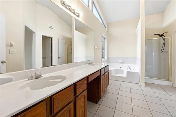 a spacious bathroom with a granite countertop sink a mirror and a bathtub