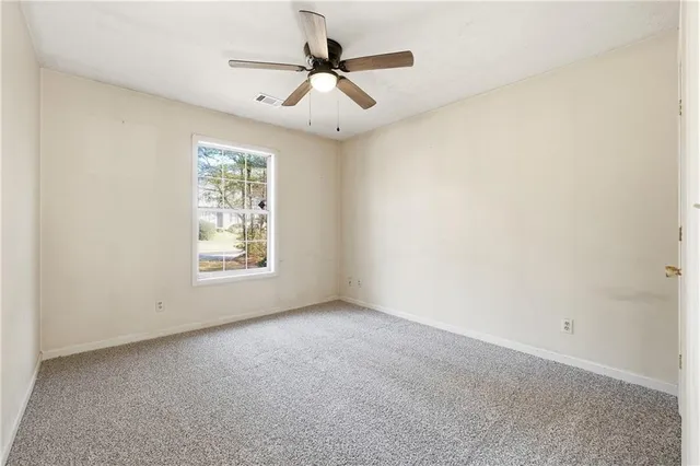 an empty room with a ceiling fan and window