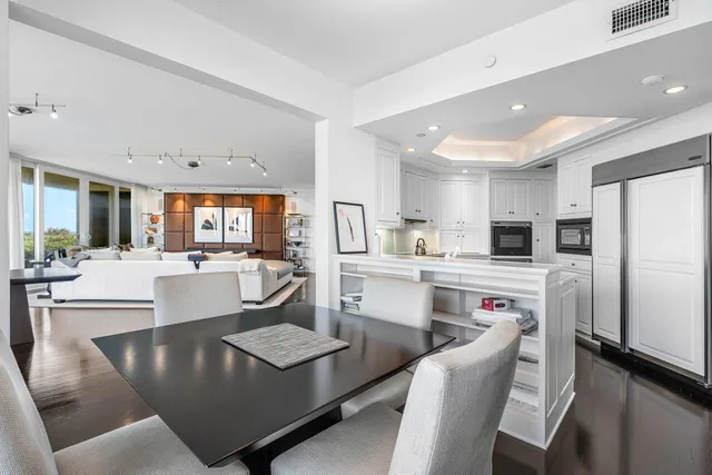 a kitchen with kitchen island stainless steel appliances sink refrigerator dining table and chairs