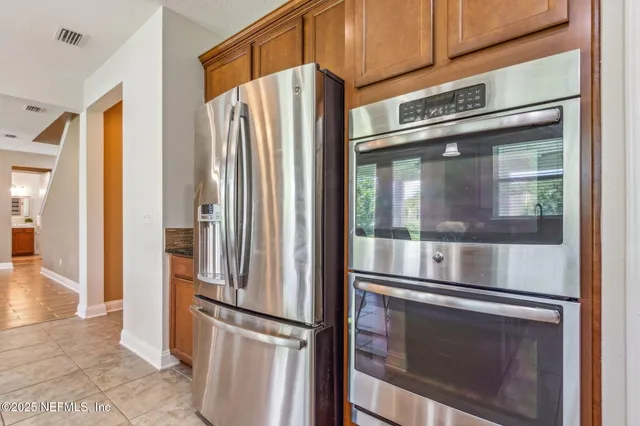 a kitchen with stainless steel appliances granite countertop a stove a sink a microwave a refrigerator and chairs