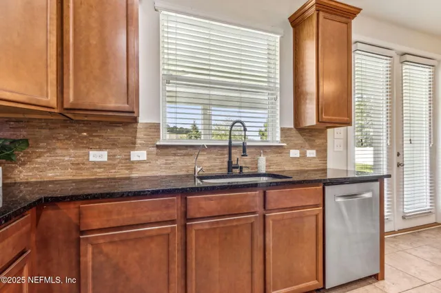 a kitchen with stainless steel appliances granite countertop a stove top oven a sink dishwasher a dining table and chairs with wooden floor