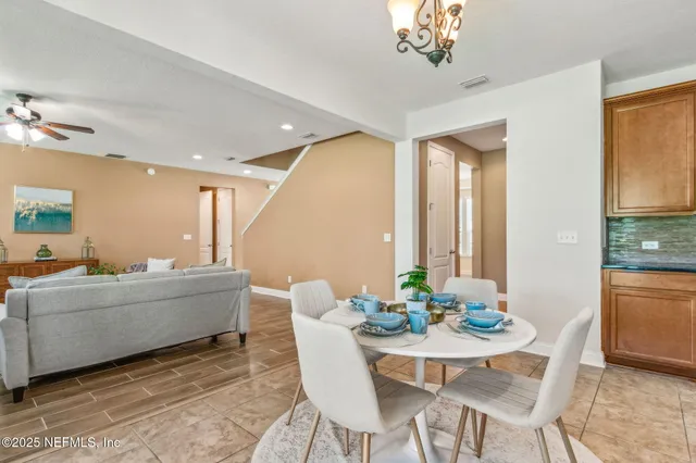 a dining room with wooden floor and a chandelier fan