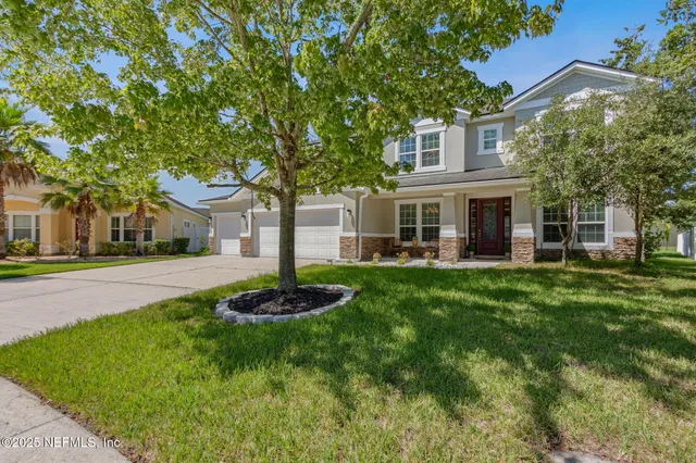 a front view of a house with a garden and trees