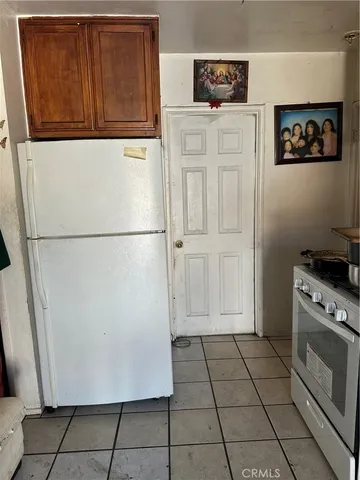 a view of a refrigerator in kitchen and white cabinets