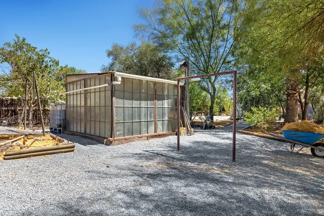 a view of a backyard with table and chairs potted plants and large tree