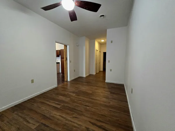 an empty room with wooden floor a ceiling fan and closet
