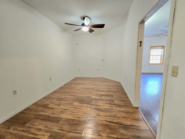 a view of a room with wooden floor and ceiling fan