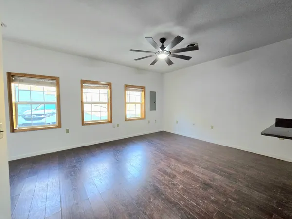 a view of an empty room with wooden floor and a window