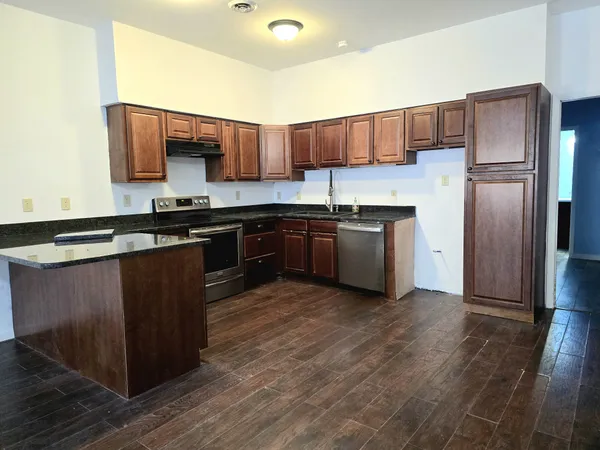 a kitchen with stainless steel appliances granite countertop wooden cabinets a refrigerator and a stove