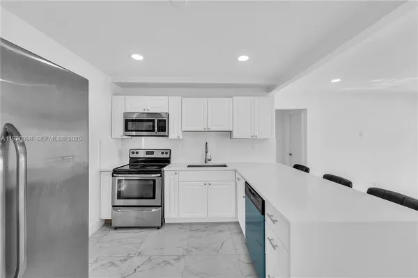 a kitchen with stainless steel appliances granite countertop a sink and a stove top oven with white countertops