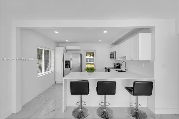 a kitchen with kitchen island a counter top space a sink stainless steel appliances and cabinets