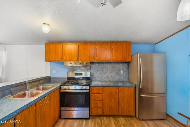a kitchen with stainless steel appliances granite countertop a refrigerator a sink dishwasher a stove and a sink