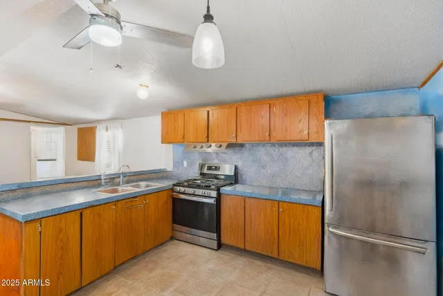 a kitchen with stainless steel appliances granite countertop a refrigerator a sink dishwasher a stove and white cabinets with wooden floor