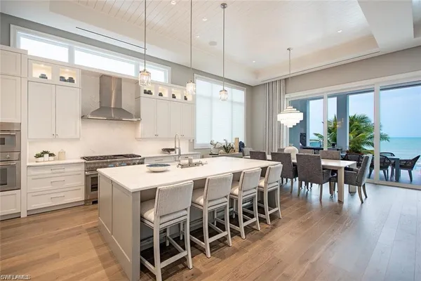 a kitchen with a dining table chairs wooden floor appliances and cabinets