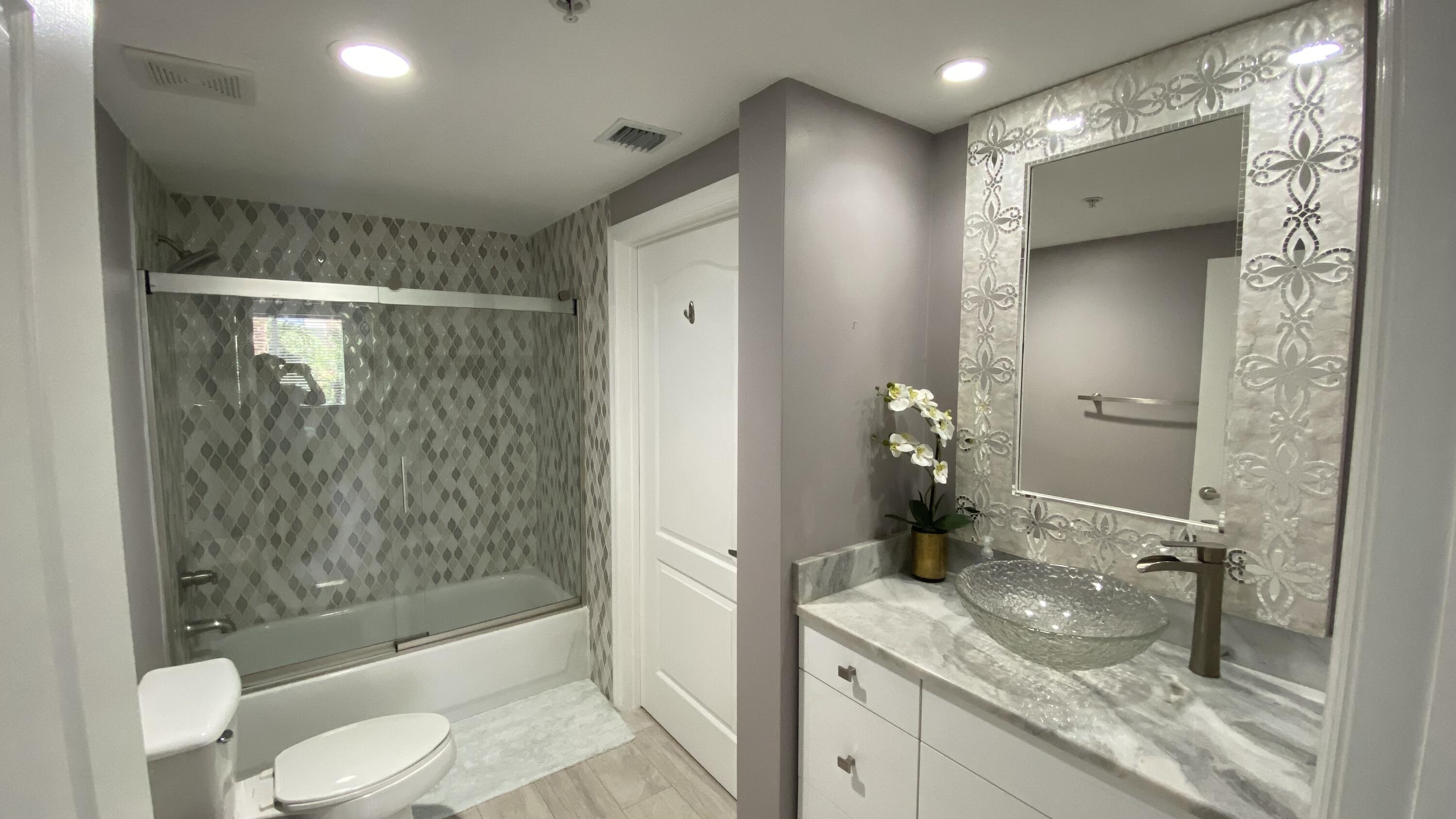 11024 Legacy Drive, Unit 104 Palm Beach Gardens, FL 33410 - Photo 14 of 26 a bathroom with a granite countertop sink toilet and shower