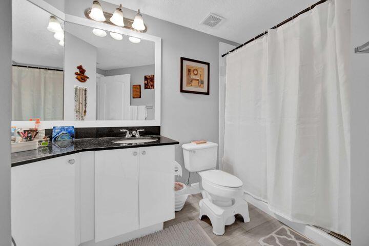 11024 Legacy Drive, Unit 104 Palm Beach Gardens, FL 33410 - Photo 17 of 26 a bathroom with a sink a toilet and a mirror