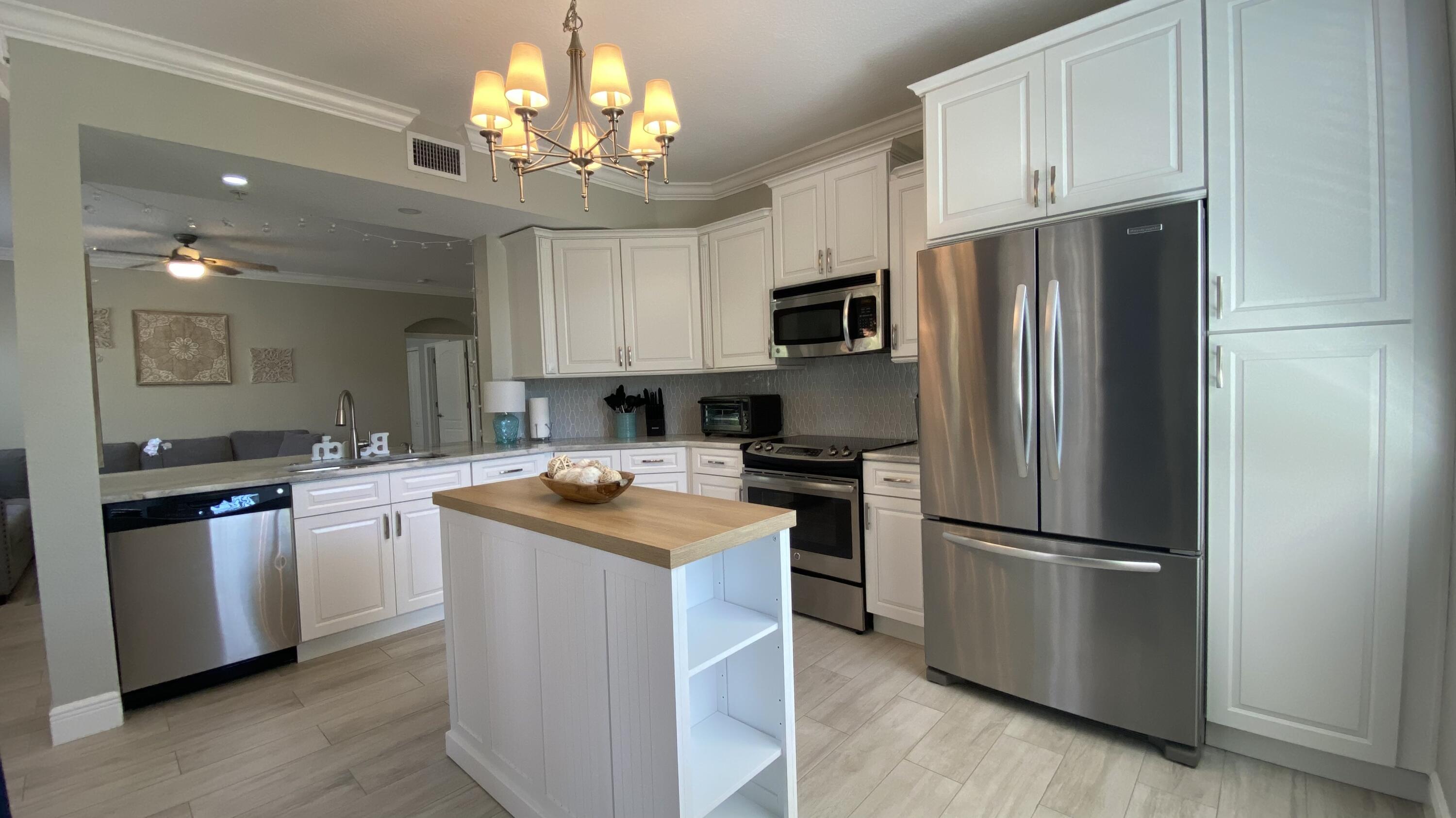 11024 Legacy Drive, Unit 104 Palm Beach Gardens, FL 33410 - Photo 8 of 26 a kitchen with stainless steel appliances granite countertop a refrigerator a stove a sink and a refrigerator