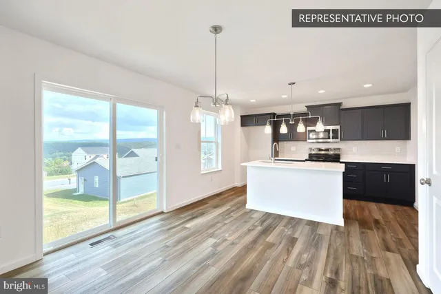 a kitchen with stainless steel appliances granite countertop a refrigerator a sink dishwasher a stove and a dining table with wooden floor