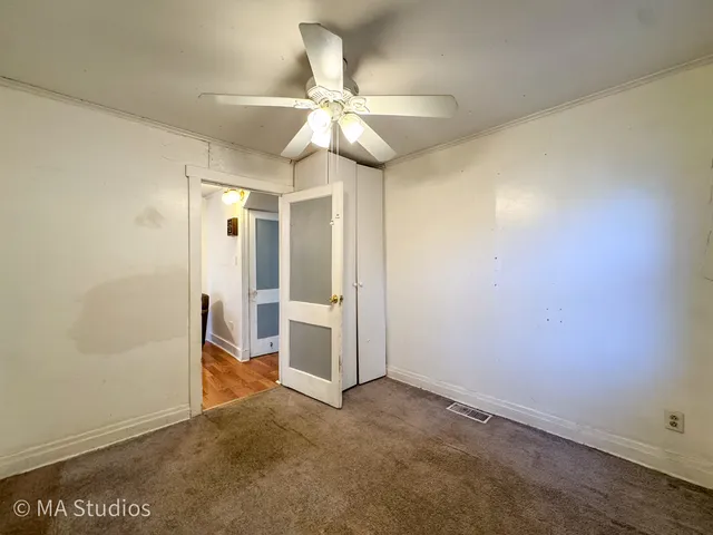 an empty room with closet and a ceiling fan