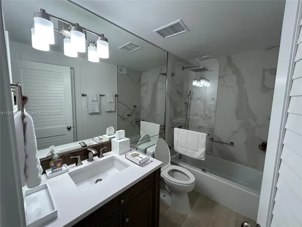 a bathroom with a toilet a sink a mirror a bathtub and shower