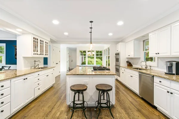 a large kitchen with granite countertop lots of counter space and wooden floor