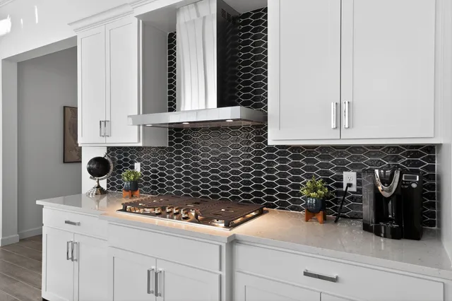 a kitchen with stainless steel appliances a sink a stove a refrigerator cabinets and wooden floor