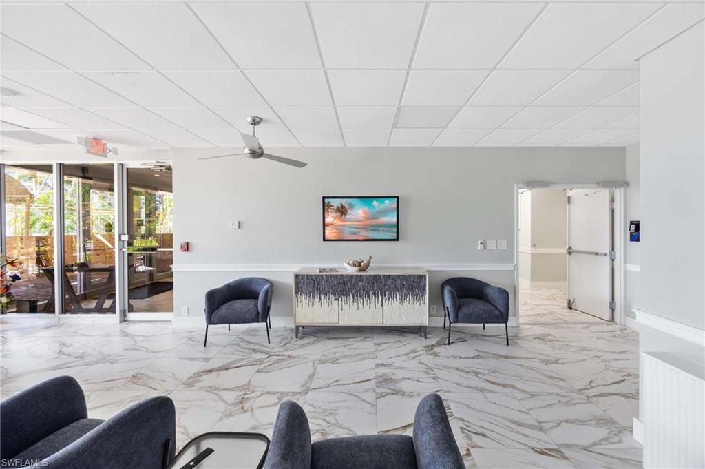 5 Bluebill Avenue, Unit 108 Naples, FL 34108 - Photo 13 of 49 Living room with a drop ceiling, marble finish floors, and a ceiling fan