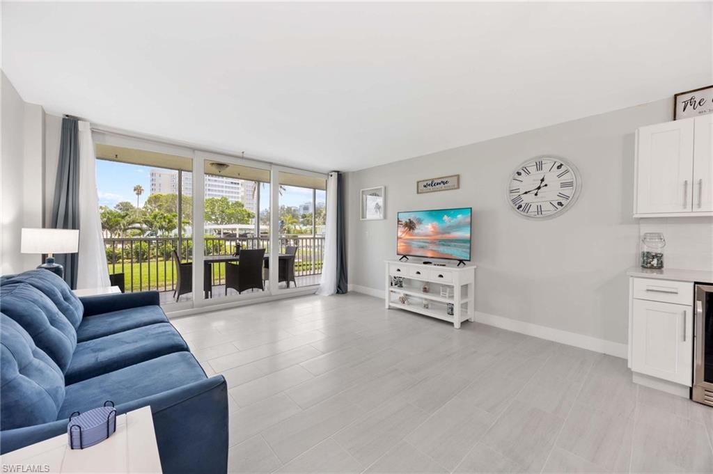 5 Bluebill Avenue, Unit 108 Naples, FL 34108 - Photo 14 of 49 Living room with a wall of windows and beverage cooler