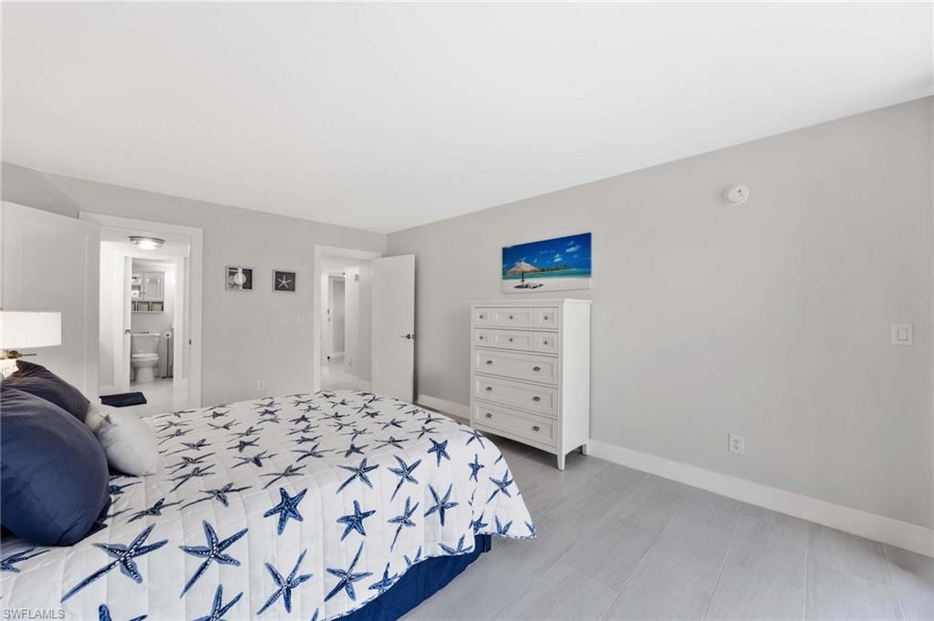 5 Bluebill Avenue, Unit 108 Naples, FL 34108 - Photo 23 of 49 Bedroom featuring baseboards and ensuite bath