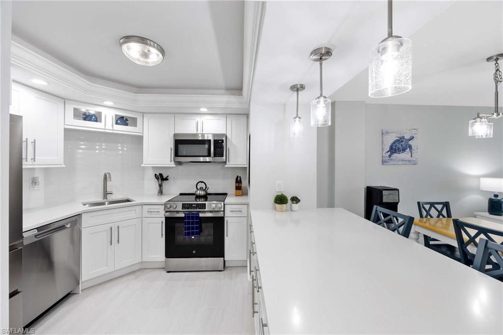 5 Bluebill Avenue, Unit 108 Naples, FL 34108 - Photo 3 of 49 Kitchen featuring appliances with stainless steel finishes, decorative backsplash, light countertops, white cabinets, and recessed lighting