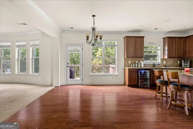 a open kitchen with granite countertop a stove top oven a dining table and chairs with wooden floor