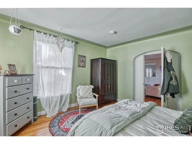 a bedroom with a bed a chair and painting on the wall